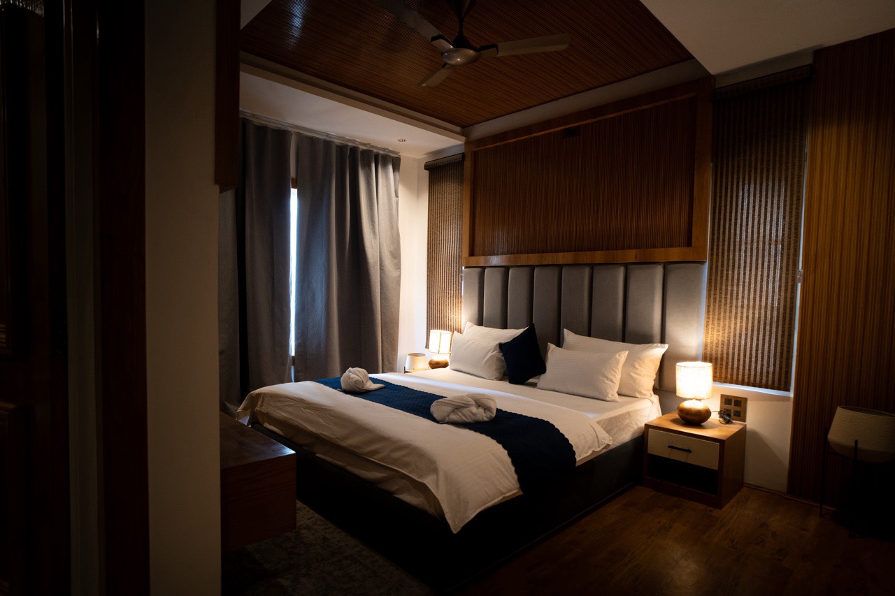 Cozy Deluxe Room bedroom interior with traditional wooden panels and warm lighting at Walnut Village Resort, Pahalgam
