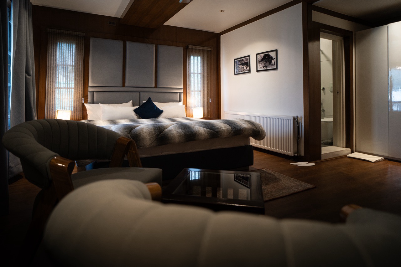 Elegant Riverview Premium room bedroom with premium bedding and a private balcony overlooking the Lidder River in Pahalgam